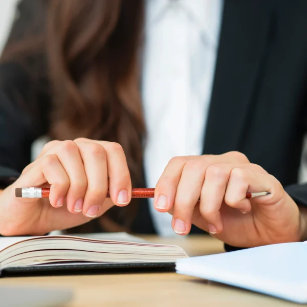 primer-plano-de-una-empresaria-sosteniendo-un-lapiz-rojo-en-sus-dos-manos-sobre-el-escritorio_11zon_11zon